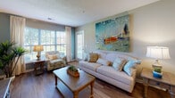 Located at 4211 Fox Rd in Raleigh, NC, this single-floor residence offers a well-designed layout that balances comfort and functionality across its key living spaces. The open-concept kitchen connects seamlessly to the living area, featuring light wood cabinetry, a peninsula with counter seating, a double sink, and white appliances. Hardwood-style flooring flows through the kitchen and into the living room, where large windows and a glass door flood the space with natural light and provide outdoor views. The living room offers generous space with neutral-toned walls that contribute to a bright, welcoming ambiance. Two bedrooms are carpeted for comfort, each equipped with ceiling fans and windows that bring in natural light. The primary bedroom is notably spacious, accommodating a full suite of furniture, and features a walk-in closet. Both bathrooms include a tub-shower combination, wood-look flooring, light wood vanity cabinetry, and well-lit mirrors. The warm, neutral color palette used throughout the residence — accented by taupe and sage tones — creates a cohesive and calming atmosphere from room to room.