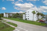 Located at 2811 Central Ave in Fort Myers, Florida, Unit 311 is a well-maintained single-floor residence featuring a bright, neutral palette and light wood-look flooring throughout. The open living area is generously proportioned, offering a clean and versatile space with smooth white ceilings and a calm, airy ambiance. A pass-through opening connects the living area to the kitchen, enhancing the sense of openness while maintaining defined functionality. The kitchen is thoughtfully appointed with white cabinetry, warm brown stone-look countertops, a double-basin stainless steel sink, and black appliances including a range and refrigerator — all set against the same light flooring that runs throughout the unit. A hallway leads to the bedroom, which features a large window that frames views of lush tropical greenery, allowing natural light to fill the room. A closet with sliding doors provides ample storage. The bathroom is finished with clean, simple lines, featuring a full soaking tub with shower surround, a toilet, and matching wood-look flooring. The overall design of the unit is understated and functional, offering a comfortable living environment in a convenient Fort Myers location.