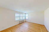 Located at 41 Garden City Dr in Cranston, Rhode Island, this two-bedroom, one-bathroom residence offers a compact and efficiently designed single-floor layout. Warm hardwood flooring flows throughout the main living areas and bedrooms, lending a classic and cohesive feel to the space.

The spacious primary bedroom is a standout feature, highlighted by a charming corner bay window arrangement that floods the room with natural light. A traditional cast-iron radiator provides reliable heating, and clean white walls create a bright, open atmosphere. The second bedroom is similarly well-appointed, featuring its own window, radiator, and a ceiling fan for added comfort.

The bathroom is finished in a timeless style, with white subway tile walls, a classic black-and-white mosaic tile floor, a soaking tub, pedestal sink, and a window for natural ventilation. Its crisp, clean aesthetic adds a touch of character to the home.

The kitchen is functional and neatly arranged, featuring warm oak cabinetry, granite-style countertops, a subway tile backsplash, a dishwasher, and a window above the sink. Light tile flooring and cream-toned walls keep the space feeling bright and welcoming.

A hallway connects the rooms efficiently, completing this well-maintained and move-in ready residence in a convenient Cranston location.