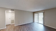 Located at 1 Aspen Dr in Greensboro, NC, this 2-bedroom, 2-bathroom residence offers a well-designed single-level layout with a practical and modern finish throughout. The open living area features wood-style plank flooring, neutral-toned walls, and a textured ceiling, creating a clean and inviting atmosphere. A large sliding glass door fitted with vertical blinds fills the space with natural light and provides direct access to the outdoors. The living area flows seamlessly into the kitchen, which is equipped with granite countertops, a subway tile backsplash, gray shaker-style cabinetry, stainless steel appliances, and track lighting overhead — offering both functionality and style. Both bedrooms are carpeted for comfort, with the primary bedroom featuring two closets, including a shelved walk-in closet. The second bedroom also includes a walk-in closet with built-in shelving. Each bathroom is tastefully appointed with granite vanity tops, undermount sinks, brushed nickel fixtures, and a tub/shower combination. A hallway connects the main living areas to the bedrooms and bathrooms, enhancing the efficient flow of the layout. This residence combines practical design with updated finishes throughout.