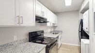 This single-floor residence offers a thoughtfully updated interior with a clean, neutral aesthetic throughout. The open living area is finished with light wood-style flooring that extends seamlessly across the space, complemented by soft gray walls and crisp white trim. A ceiling fan with integrated lighting serves as a functional centerpiece, while a window fitted with horizontal blinds allows natural light to filter in, enhancing the airy feel of the room.

The kitchen is designed in a galley layout, featuring white shaker-style cabinetry with brushed nickel hardware and granite-look countertops. A black electric range with a range hood sits alongside a stainless steel sink, and a skylight overhead adds additional brightness to the workspace. Notably, the kitchen also accommodates a stacked in-unit washer and dryer, providing added convenience.

The bedrooms continue the consistent flooring and neutral palette, each equipped with ceiling fans and closet storage. Multiple doorways and open closet configurations offer practical storage solutions. The overall design prioritizes functionality and a cohesive, move-in-ready appearance, with clean finishes and consistent materials tying the entire space together.