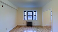 Located at 58 N Lansdowne Avenue in Lansdowne, Pennsylvania, this single-floor space combines classic architectural character with a clean, updated aesthetic. The interior showcases gleaming hardwood floors that run throughout, reflecting natural light and adding warmth to the overall ambiance. Crisp white trim and soft, neutral-toned walls create a bright and inviting atmosphere. A standout feature of the main living area is the large multi-pane window set with bold black frames, allowing ample natural light to flood the room while offering pleasant views of the surrounding neighborhood. Beneath the window, a traditional cast-iron radiator serves as both a functional heating element and a charming nod to the building's historic character. The high placement of the ceiling contributes to a sense of openness and spaciousness throughout the room. A wide doorway connects the living space to an adjacent room, suggesting a practical and flowing floor plan. The overall design balances vintage details — such as the radiator and classic window styling — with fresh, well-maintained finishes, making this a space that feels both timeless and move-in ready. Situated in the borough of Lansdowne, the property offers convenient access to the surrounding Delaware County community.
