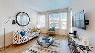 Located at 3100 Central Ave in Saint Petersburg, FL, this well-designed 2-bedroom, 2-bathroom residence offers a thoughtfully arranged single-level floor plan. The open-concept kitchen and living area serves as the heart of the home, featuring crisp white shaker cabinetry, stainless steel appliances including a refrigerator, range, microwave, and dishwasher, along with light-toned countertops and durable wood-style flooring. Pendant lighting over the kitchen island adds a modern touch, while the space flows seamlessly into the bright living room, which is bathed in natural light through a bank of large windows dressed with sheer curtains and blinds. The primary bedroom is a comfortable retreat, complete with plush carpeting, a walk-in closet, and a private en-suite bathroom featuring a tiled tub/shower combination with brushed gold fixtures. The second bedroom also offers carpeted floors and multiple windows with views of the surrounding area. A second full bathroom mirrors the clean, white-tiled aesthetic of the primary bath. The unit's consistent use of neutral tones, white finishes, and natural light creates a cohesive, airy ambiance throughout the entire space.