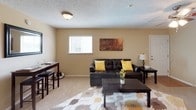 This single-floor residence offers a thoughtfully designed layout with a cohesive warm, neutral color palette carried throughout each room. The living area serves as the heart of the space, featuring plush carpeted flooring, a ceiling fan with integrated lighting, and natural light streaming through a window fitted with blinds. The open, comfortable layout provides ample room for both relaxing and entertaining.

The kitchen is outfitted with white cabinetry offering generous storage, light-toned countertops, a double-basin stainless steel sink, and a dishwasher. Wood-look flooring adds a practical and clean aesthetic to this functional cooking space.

Two bedrooms provide restful retreats, each carpeted and equipped with ceiling fans for year-round comfort. Both rooms feature windows that invite natural light and offer enough space for full bedroom furniture arrangements. One bedroom benefits from direct access to an adjoining room, adding convenience to the layout.

The bathroom is neatly finished with white cabinetry, a single-sink vanity with a large mirror, and a shower-tub combination. Textured ceilings are a consistent architectural detail found throughout the space, lending a classic residential character. Overall, the residence presents a practical and comfortable living environment with a consistent, inviting design.
