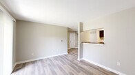 Located at 1326 Mcintosh Ln in Anderson, Indiana, this single-story, 2-bedroom, 2-bathroom home offers a clean, modern aesthetic with a neutral color palette throughout. Light-toned luxury vinyl plank flooring runs across the main living areas, complementing the crisp white trim and warm greige walls to create a bright, cohesive interior.

The open living room is a welcoming space anchored by a large sliding glass door dressed with vertical blinds, flooding the room with natural light. It flows seamlessly into the kitchen area via a half-wall pass-through with a granite-style countertop overhang. The galley kitchen is well-appointed with dark espresso cabinetry, granite-look countertops, a stainless steel sink, and black appliances including a range and refrigerator, with ample upper and lower cabinet storage.

The primary bedroom offers a comfortable footprint with its own walk-in closet featuring built-in shelving. The second bedroom includes a window with natural views and matching LVP flooring. Both bathrooms are finished in a clean, simple style, with one featuring a full tub-shower combination with white tile surround and brushed nickel fixtures. Two dedicated closets add practical storage throughout the home.