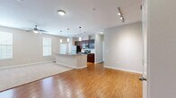 This single-floor residence offers a thoughtfully designed layout across two bedrooms and two bathrooms. The open-concept living and kitchen area serves as the heart of the home, featuring warm hardwood-style flooring that transitions seamlessly into plush carpeting in the living zone. The kitchen is equipped with stainless steel appliances, including a refrigerator, microwave, and range, complemented by rich dark espresso cabinetry and a granite-topped island with pendant lighting overhead. Track lighting further illuminates the space, adding a modern touch. The living area is bright and airy, with a ceiling fan and multiple windows allowing natural light to fill the room. A glass-panel door provides additional access and light. Both bedrooms are carpeted and feature ceiling fans, ample natural light from large windows, and a calm, neutral color palette. The primary bedroom offers a comfortable footprint well-suited for a full furniture arrangement. The two bathrooms are finished with tile flooring, dark wood vanities, granite countertops, and framed mirrors. One bathroom includes a tub-shower combination with decorative tile accents. A dedicated closet and hallway complete the functional layout of this well-designed residence.