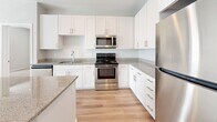 This well-designed 2-bedroom, 1-bathroom residence in Denver, Colorado offers a clean, modern aesthetic throughout its single-floor layout. The kitchen serves as the centerpiece of the home, showcasing white shaker cabinetry, granite countertops, a stainless steel appliance suite including a refrigerator, range, microwave, and dishwasher, and a central island that provides additional prep space and casual seating. Light wood-tone flooring runs through the main living and kitchen areas, lending warmth and continuity to the space. Both bedrooms are carpeted and finished with neutral-toned walls, offering a calm and comfortable atmosphere. Natural light enters through window-blind-fitted windows, brightening each room. The primary bedroom provides a generous footprint, while the second bedroom is well-proportioned for flexible use. Three closets throughout the unit offer practical storage solutions. The bathroom features a clean walk-in shower with built-in shelving. Recessed lighting in the kitchen adds a polished touch, and the overall neutral color palette creates a bright, cohesive feel. The entry area includes a utility panel, adding everyday convenience. Located in Denver's 80203 zip code, this residence combines functional design with modern finishes.