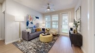 This single-story, 2-bedroom, 2-bathroom residence offers a thoughtfully designed open-concept layout that seamlessly connects the kitchen and living areas. The kitchen is a standout feature, equipped with crisp white shaker cabinetry, stainless steel appliances including a French door refrigerator and range, a subway tile backsplash, and a peninsula with seating — ideal for casual dining or entertaining. The living room is bright and welcoming, with a ceiling fan, large windows, and a glass door that invites natural light and provides access to the outdoors. Warm hardwood-style flooring runs throughout the entire residence, creating a cohesive and clean aesthetic. The primary bedroom is a comfortable retreat, supported by two walk-in closets with built-in shelving and hanging rods offering generous storage. The en-suite bathroom features a double vanity with white cabinetry, quartz countertops, and a large mirror. The second bedroom also benefits from natural light through dual windows and its own ceiling fan. Additional highlights include five closets total, a dedicated laundry area, and a neutral gray-toned color palette throughout. The layout is practical and efficient, making excellent use of the available floor space.
