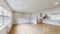 This thoughtfully renovated single-floor space offers a clean, modern aesthetic with a cohesive neutral color palette and light hardwood flooring that flows seamlessly throughout. The open-concept living and dining area is generously proportioned, bathed in natural light, and illuminated by recessed ceiling lights that enhance the airy ambiance. A large pass-through connects the living area to the kitchen, maintaining an open and connected feel.

The kitchen is a standout feature, boasting light wood cabinetry with open shelving, a crisp white quartz countertop, a mosaic tile backsplash, and a full suite of stainless steel appliances including a gas range, microwave, dishwasher, and refrigerator. A peninsula with elegant pendant lighting serves as both a functional workspace and a casual dining area.

The bedrooms are well-sized, each featuring hardwood floors, neutral walls, and windows that invite natural light and outdoor views of surrounding greenery. Several rooms include wall-mounted AC units and baseboard heating for year-round comfort. Closet space is available in the bedrooms, adding practical storage. White trim and doors throughout provide a polished, cohesive finish that ties the entire space together.