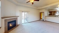 Located at 314 Founders Park Dr in Rapid City, South Dakota, this 2-bedroom, 2-bathroom residence offers a well-designed single-floor layout with a thoughtful mix of comfort and functionality. The open-concept living and dining area is anchored by a tile-surround fireplace and features a tray ceiling, plush carpeting, and a window that fills the space with natural light. The kitchen is equipped with rich dark-wood cabinetry, granite-style countertops, stainless steel appliances including a side-by-side refrigerator, range, and microwave, along with a breakfast bar and pendant lighting. Both bedrooms are generously sized, carpeted, and fitted with ceiling fans. The spacious primary bedroom includes a sliding glass door that opens to a private balcony and direct access to its en-suite bathroom, which features a wide vanity with ample cabinetry and a large mirror. The second bathroom offers a full tub-shower combination. Three closets provide abundant storage throughout. A dedicated in-unit laundry room includes full-size washer and dryer units with overhead shelving. The private balcony extends the living space outdoors, completing this well-appointed residence.