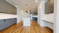 This 690 sq ft, 1-bedroom, 1-bathroom apartment in Argyle, TX offers a clean, modern design with consistent white walls and crisp trim. The open-concept kitchen and living area features light hardwood-style flooring, gray shaker cabinetry, quartz countertops, stainless steel appliances, a central island with pendant lighting, and recessed fixtures. The 170 sq ft bedroom includes plush carpet, a ceiling fan, and a large window with natural light. The bathroom is appointed with gray vanity cabinetry, black hardware accents, a tiled tub/shower combo, and hardwood-style flooring. A dedicated closet completes the layout.