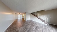 Located at 16211 Parkside Ln in Huntington Beach, California, this two-story, 2-bedroom, 2-bathroom home is thoughtfully laid out across two floors. The main level features a spacious living room with durable wood-style plank flooring, neutral toned walls, a ceiling fan, and a textured ceiling. The open flow leads to a galley-style kitchen equipped with white cabinetry, granite-style countertops, a stainless steel gas range, built-in microwave, dishwasher, and a white refrigerator — all set atop matching wood-style flooring. A staircase with white metal railings connects the main level to the upper floor. Upstairs, both bedrooms are generously sized and finished with plush carpeting and textured ceilings. The spacious primary bedroom includes mirrored sliding closet doors and a window with views of an outdoor balcony. The second bedroom is well-proportioned with its own window and balcony access. Two full bathrooms serve the home; one features an extended vanity with a granite-style countertop, white cabinetry, a tub/shower combo, and wood-style flooring, while the second bath offers a similarly clean, bright aesthetic with a granite-topped vanity and large mirror.