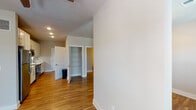 This single-floor studio in Panama City Beach, Florida offers a thoughtfully designed open layout that maximizes every square foot. Warm hardwood-style flooring extends throughout the space, complementing the neutral wall tones and creating a cohesive, inviting atmosphere. The living area is bathed in natural light through large windows and French doors, which also provide access to the outdoors. A ceiling fan adds comfort and enhances airflow throughout the main living space.

The galley-style kitchen is a standout feature, outfitted with full stainless steel appliances — including a refrigerator, electric range, over-the-range microwave, and dishwasher — alongside crisp white shaker cabinetry that extends to the ceiling for ample storage. White quartz countertops and a classic subway tile backsplash complete the clean, modern aesthetic, while a stainless steel sink adds a polished finishing touch.

The bathroom is efficiently designed with a glass-enclosed walk-in shower featuring white tile surround and brushed nickel hardware. Additional storage is provided by a built-in open shelving closet, ideal for organization. Recessed lighting throughout ensures the space remains bright and functional. This studio combines contemporary finishes with practical design in a desirable coastal Florida location.