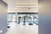 Located at 217 S Weber St in Colorado Springs, CO, this modern fitness center offers a thoughtfully designed workout environment on a single floor. The space is defined by expansive floor-to-ceiling windows that run along multiple walls, flooding the interior with natural light and providing views of the surrounding Colorado Springs streetscape and mountain skyline. The clean, light-toned flooring and crisp white ceiling with sleek linear lighting fixtures contribute to a bright, open atmosphere.

Bold navy blue accent walls punctuate the interior, adding a contemporary, energetic character to the space. The fitness center is comprehensively equipped to support a full range of workouts. Cardio equipment includes multiple treadmills and stationary bikes, including upright and cycling-style options, all positioned to take advantage of the street-facing windows. A multi-station cable and strength machine anchors one end of the floor plan, complemented by adjustable weight benches, resistance training accessories, and functional fitness equipment. A well-stocked free weights section features a tiered dumbbell rack alongside a full set of kettlebells of varying weights, accommodating all fitness levels.

Exposed concrete structural columns add an industrial design element that contrasts with the polished finishes throughout. The overall layout provides ample circulation space, making the fitness center both functional and inviting.