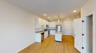 This single-floor residence offers a clean, contemporary design with a thoughtful layout and quality finishes throughout. The open kitchen serves as the heart of the space, showcasing crisp white shaker-style cabinetry, granite countertops, and a full suite of stainless steel appliances including a refrigerator, electric range, over-the-range microwave, and dishwasher. A central island with a pendant light above provides additional prep and gathering space, while light hardwood-style flooring ties the kitchen and adjoining open area together seamlessly. Recessed lighting throughout the kitchen ensures a bright, functional environment. The bedroom is a calm, neutral retreat featuring plush wall-to-wall carpeting and a pair of double windows fitted with horizontal blinds, allowing for natural light and outdoor views. The bathroom is finished with a granite-topped vanity with an undermount sink, a toilet, and a combined tub and shower enclosure, all presented in a clean, neutral palette. The overall ambiance of the space is modern and move-in ready, with consistent neutral tones, quality materials, and practical finishes that create a comfortable and welcoming living environment.