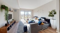 Located at 880 Pacific St in Stamford, Connecticut, this modern one-bedroom, one-bathroom residence offers a well-designed single-floor layout that balances comfort and contemporary style. The open-concept living and kitchen area serves as the heart of the home, bathed in natural light streaming through large sliding glass doors that lead to an outdoor space and frame views of the surrounding neighborhood. Warm hardwood-style flooring flows throughout, complementing the neutral, light-toned walls.

The kitchen is outfitted with light wood cabinetry extending to the ceiling, a white subway tile backsplash, stainless steel appliances including a gas range, microwave, and refrigerator, and a freestanding island with bar seating — ideal for casual dining or meal prep. The entry foyer provides a clean transition into the main living space.

The bedroom is generously proportioned, filled with natural light from a wide window with outdoor views, and includes access to a walk-in closet as well as a dedicated bathroom entry. The bathroom features wood-tone flooring, a backlit vanity mirror, a light blue vanity cabinet with a sleek countertop, and a full tub-shower combination with white tile surround. The overall ambiance is clean, bright, and move-in ready.