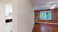 Located at 637 N Bronson Ave in the vibrant Larchmont Village neighborhood of Los Angeles, this single-floor residence combines classic character with functional design. The living area is a standout, showcasing a striking exposed brick accent wall paired with rich hardwood flooring and a ceiling fan with integrated lighting. A large window frames lush greenery outside, filling the room with natural light and a sense of connection to the outdoors.

The galley-style kitchen is efficiently laid out with white cabinetry, dark granite countertops, a stainless steel sink, light tile flooring, and a full suite of white appliances including a gas range and refrigerator. Ample upper and lower cabinet storage makes the most of the space.

The bedroom continues the warm hardwood flooring theme and features a ceiling fan with recessed lighting, creating a comfortable and well-lit retreat. The entryway is finished in clean tile flooring, providing convenient access to both the bathroom and an adjacent closet.

The bathroom is thoughtfully appointed with classic white hex tile flooring accented by a subtle floral detail, white subway wall tiles, a tub-shower combination with sliding glass doors, and a clean white vanity. Throughout the unit, a consistent palette of white walls and warm wood tones creates a cohesive, inviting ambiance.