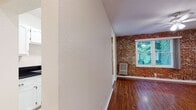 Located at 637 N Bronson Ave in the vibrant Larchmont Village neighborhood of Los Angeles, this single-floor residence combines classic character with functional design. The living area is a standout, showcasing a striking exposed brick accent wall paired with rich hardwood flooring and a ceiling fan with integrated lighting. A large window frames lush greenery outside, filling the room with natural light and a sense of connection to the outdoors.

The galley-style kitchen is efficiently laid out with white cabinetry, dark granite countertops, a stainless steel sink, light tile flooring, and a full suite of white appliances including a gas range and refrigerator. Ample upper and lower cabinet storage makes the most of the space.

The bedroom continues the warm hardwood flooring theme and features a ceiling fan with recessed lighting, creating a comfortable and well-lit retreat. The entryway is finished in clean tile flooring, providing convenient access to both the bathroom and an adjacent closet.

The bathroom is thoughtfully appointed with classic white hex tile flooring accented by a subtle floral detail, white subway wall tiles, a tub-shower combination with sliding glass doors, and a clean white vanity. Throughout the unit, a consistent palette of white walls and warm wood tones creates a cohesive, inviting ambiance.