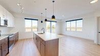 This thoughtfully designed 3-bedroom, 2-bathroom residence in Farmington, MN offers a clean, modern aesthetic with light-toned hardwood flooring and crisp white walls extending throughout the single-floor layout. The open-concept kitchen and living area serves as the heart of the home, anchored by a generous island with a quartz countertop, an integrated sink with a matte black faucet, and striking black pendant lights overhead. The kitchen features two-tone cabinetry—warm wood lower cabinets paired with white uppers—complemented by a tiled backsplash and stainless steel appliances. A dedicated pantry provides additional storage. Multiple windows bathe the living area in natural light and offer outdoor views, with direct access to a private balcony. The primary bedroom is a comfortable retreat with ample space and a walk-in closet equipped with wire shelving. Two additional bedrooms feature light-filled windows and good-sized closets. The primary bathroom impresses with a double-sink vanity, warm wood cabinetry, white quartz countertops, and matte black and gold hardware. A dedicated laundry room and utility room add everyday convenience. Hallways connect the spaces smoothly, reinforcing the home's well-organized and functional floor plan.