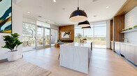 Located in Folsom, CA, this thoughtfully designed leasing office delivers a polished, contemporary experience across a single floor. The open reception area greets visitors with soaring ceilings, light hardwood flooring, and a bold large-scale artwork anchoring the entryway. Abundant natural light pours in through floor-to-ceiling windows and glass doors, offering views of the surrounding outdoor spaces.

At the heart of the main area sits a stunning waterfall-edge marble island, suspended beneath a trio of oversized matte black pendant lights. The adjacent kitchen is fully equipped with warm wood cabinetry, a textured white tile backsplash, integrated appliances, and counter seating — ideal for hosting prospective residents or staff. Open shelving with live greenery adds a fresh, organic element to the space.

The private manager's office is enclosed with sleek glass walls and a glass door, maintaining visual connectivity while ensuring privacy. Inside, natural light continues to flood the space through additional large windows, complemented by patterned carpet, a wood-toned desk, and comfortable seating. A connecting hallway provides seamless flow between the functional areas. Throughout, the design balances professionalism with warmth, creating a welcoming environment for visitors and staff alike.