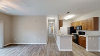 Located at 501 Hinson Dr in Myrtle Beach, SC, this well-appointed 3-bedroom, 2-bathroom single-floor unit offers a comfortable and functional layout designed for everyday living. The galley-style kitchen is a standout feature, boasting warm wood-toned cabinetry, granite-look countertops, black appliances including a range and built-in microwave, a double basin sink, and durable wood-look plank flooring that extends throughout the main living areas. Track and flush-mount lighting keep the kitchen bright and practical. The open living area benefits from the same wood-look flooring and features a ceiling fan and sliding glass doors that lead to a private balcony, inviting natural light and outdoor views. Each of the three bedrooms is finished with plush carpeting, ceiling fans, and windows dressed with white blinds that provide a soft, natural glow. The primary bedroom offers a generous footprint with ample room for furnishings. Three closets throughout the unit provide excellent storage. Both bathrooms feature tub-shower combinations with white surrounds and accessibility-focused grab bars with brushed nickel finishes. A dedicated laundry area with hookups adds convenience. Neutral tones and clean finishes throughout lend the space a calm, move-in-ready ambiance.
