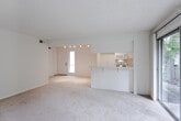 Located at 1201 Fairhaven Ave in Santa Ana, CA, this single-floor unit offers a thoughtfully arranged open-concept layout that connects the kitchen and living areas seamlessly. The kitchen is well-appointed with white cabinetry, ample counter space, a gas range, built-in microwave, and a double-basin sink. A skylight and a garden-facing window flood the kitchen with natural light, while rich hardwood flooring adds warmth underfoot. Track lighting overhead provides additional illumination throughout the kitchen and adjoining dining area. The living area transitions smoothly from the kitchen via a peninsula counter and features neutral carpet flooring throughout. A full wall of sliding glass doors opens to a verdant outdoor patio surrounded by lush greenery, bringing the outdoors in and filling the space with abundant natural light. The bedrooms are generously sized, each finished with plush carpet and featuring louvered closet doors for built-in storage. One bedroom includes an en-suite bathroom and a walk-in closet. Windows in the bedrooms frame views of the surrounding landscaping, maintaining a bright and airy atmosphere throughout. The textured ceilings and clean neutral walls provide a consistent, understated backdrop across all rooms, lending the space a calm, functional character well-suited for comfortable everyday living.