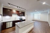 Located at Century Square in College Station, TX, this well-appointed 2-bedroom, 3-bathroom unit offers a thoughtfully designed single-floor layout. The open-concept kitchen is a standout feature, showcasing rich dark cabinetry, a granite-topped central island, stainless steel appliances including a refrigerator, dishwasher, microwave, and electric range, along with a tile backsplash and track lighting overhead. Durable hardwood-style flooring extends through the kitchen and living areas, adding warmth and continuity to the space.

The primary bedroom is generously sized, featuring a ceiling fan and a large window with blinds that invite natural light. It connects to a spacious en-suite bathroom with a granite-topped vanity, a soaking tub with shower, large-format tile flooring, and a framed mirror. A dedicated walk-in closet with wire shelving provides ample storage.

The second bedroom also benefits from natural light through a window with blinds and is finished with plush carpeting and a ceiling fan. Both bedrooms access well-appointed bathrooms. Connecting hallways are finished in light tile, and the overall color palette of crisp white walls and neutral tones creates a clean, modern ambiance throughout the unit.