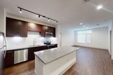 Located at Century Square in College Station, TX, this well-appointed 2-bedroom, 3-bathroom unit offers a thoughtfully designed single-floor layout. The open-concept kitchen is a standout feature, showcasing rich dark cabinetry, a granite-topped central island, stainless steel appliances including a refrigerator, dishwasher, microwave, and electric range, along with a tile backsplash and track lighting overhead. Durable hardwood-style flooring extends through the kitchen and living areas, adding warmth and continuity to the space.

The primary bedroom is generously sized, featuring a ceiling fan and a large window with blinds that invite natural light. It connects to a spacious en-suite bathroom with a granite-topped vanity, a soaking tub with shower, large-format tile flooring, and a framed mirror. A dedicated walk-in closet with wire shelving provides ample storage.

The second bedroom also benefits from natural light through a window with blinds and is finished with plush carpeting and a ceiling fan. Both bedrooms access well-appointed bathrooms. Connecting hallways are finished in light tile, and the overall color palette of crisp white walls and neutral tones creates a clean, modern ambiance throughout the unit.