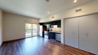 Located at 2645 Railroad Street in Pittsburgh's Strip District, this efficiently designed studio offers a thoughtful layout across a single floor. The open-concept kitchen and living area forms the heart of the unit, featuring rich hardwood-style flooring, recessed lighting, and a sliding glass door that floods the space with natural light and provides direct access to a private balcony with outdoor views. The kitchen is outfitted with dark cabinetry that extends to the ceiling, granite-look countertops, a stainless steel appliance suite including a refrigerator, range, microwave, and dishwasher, and a single-basin sink. The living area offers an open, flexible space with neutral walls and clean lines. A dedicated hallway connects the main living space to the bathroom, which features a full soaking tub and shower combination, hardwood-style flooring, and a dark-cabinet vanity with a granite-look countertop. Two closets provide generous storage, while a dedicated laundry area and utility room add everyday convenience. The unit's modern, minimalist design is consistent throughout, with flat-panel doors, sleek hardware, and a neutral color palette creating a cohesive and contemporary ambiance.