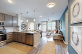 Located at 16200 Croft Drive in Charlotte, NC, this single-floor, 2-bedroom, 2-bathroom residence offers a thoughtfully designed open-concept layout. The combined kitchen and living area serves as the heart of the home, where wood-look flooring flows seamlessly throughout. The kitchen is equipped with stainless steel appliances, taupe cabinetry, a subway tile backsplash, granite countertops, and a large center island with pendant lighting — ideal for both cooking and casual dining. The living room is anchored by a bold teal accent wall and ceiling fan, with large windows allowing generous natural light and outdoor views. The primary bedroom features a distinctive arched teal accent wall, plush carpeting, a ceiling fan, and a walk-in closet outfitted with wire shelving. The second bedroom is well-sized with a ceiling fan and a large window overlooking greenery. Both bathrooms feature granite vanities, wood-look tile flooring, and tub-shower combinations. A dedicated laundry room with side-by-side washer and dryer hookups adds everyday convenience. Two closets provide ample storage throughout the residence.