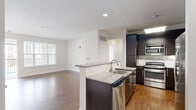 This 2-bedroom, 3-bathroom residence is designed with a functional and modern aesthetic throughout its single-floor layout. The open-concept kitchen and living area serves as the heart of the home, featuring rich hardwood-style flooring, crisp white walls, and abundant natural light from multiple windows with blinds. The kitchen is outfitted with dark espresso cabinetry, granite countertops, a peninsula with a double sink and dishwasher, and a full suite of stainless steel appliances, including a range, microwave, and refrigerator. A tile backsplash adds a refined finishing touch. The spacious living room flows seamlessly from the kitchen, providing an open and airy atmosphere. The generously sized primary bedroom includes plush carpeting, a ceiling fan, a large window with outdoor views, and access to a walk-in closet with wire shelving. The bathrooms are finished with granite vanity countertops, dark cabinetry, framed mirrors, and tile flooring; one features a towel warmer bar and pendant lighting for an elevated feel, while another includes a tub-shower combo. A dedicated laundry room houses a full-size washer and dryer with overhead shelving, adding everyday convenience to this well-designed residence.