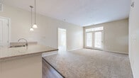 Located at 5101 Water St in Milford, Ohio, this single-floor, two-bedroom, two-bathroom residence offers a comfortable and well-designed layout. The open-concept living and kitchen area serves as the heart of the home, where hardwood-style flooring flows through the kitchen and transitions into plush carpeting in the living room. The kitchen is equipped with stainless steel appliances, warm wood cabinetry, a granite-topped breakfast bar with pendant lighting, and a sink overlooking the living space. French doors in the living room welcome natural light and provide access to an outdoor deck. The primary bedroom is generously sized, featuring multiple windows that offer neighborhood views and ample natural light. Both bedrooms are carpeted and connect to dedicated closets, with the unit offering four closets in total for excellent storage capacity. The two bathrooms are well-appointed: one features a sliding-door enclosed shower with tile surround and hardwood-style flooring, while the second includes a soaking tub with full tile surround. A dedicated utility room and a convenient hallway complete the layout. Neutral tones throughout create a clean, move-in ready atmosphere suited for a variety of living styles.