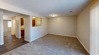 Located at 2614 S Topeka St, Unit 207 in Wichita, Kansas, this one-bedroom, one-bathroom unit offers a thoughtfully organized single-floor layout. The living area is generously proportioned with neutral-toned carpet, textured ceilings, and a pass-through window connecting to the kitchen, which features warm wood-toned cabinetry. This open visual connection between the living and kitchen spaces enhances the sense of openness throughout. The bedroom is a comfortable, private retreat finished with plush carpet, soft gray walls, a window with blinds that allows natural light to filter in, and a mirrored sliding-door closet that adds depth and storage functionality. The hallway provides a logical transition between rooms, contributing to the unit's efficient flow. The full bathroom is well-appointed with a combination tub and shower, a wood-vanity with storage, a toilet, and durable wood-look vinyl flooring that adds a clean, modern contrast to the warm tones of the rest of the unit. Throughout the space, consistent finishes including neutral paint, textured ceilings, and practical flooring choices create a cohesive and functional living environment suited for everyday comfort.