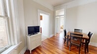 Located at 641 O'Farrell Street in San Francisco, this one-bedroom, one-bathroom unit offers a practical and well-organized layout across a single floor. Rich hardwood flooring flows throughout the main living areas, complemented by classic crown molding that lends a traditional architectural character to the space.

The combined living and dining area provides a comfortable, open feel. The living room features a large window that lets in natural light and offers views of the surrounding streetscape, while the dining area accommodates a four-seat table and sits adjacent to the kitchen for convenient everyday living.

The kitchen is outfitted with warm-toned wood cabinetry, tile countertops, and light tile flooring. It is compact yet functional, equipped with a refrigerator, stovetop, and microwave.

The bedroom is notably spacious, featuring a bank of large windows framing expansive city views and allowing ample natural light to fill the room. Hardwood floors, high ceilings, and a closet round out this well-proportioned retreat.

The bathroom is clean and straightforward, featuring a pedestal sink, toilet, tile flooring, and a window that provides natural ventilation and light. A hallway connects the rooms, maintaining a logical and efficient flow throughout the unit.
