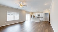 This single-floor home offers a thoughtfully designed open-concept layout that seamlessly connects the living, dining, and kitchen areas. Rich, dark hardwood flooring runs throughout the entire home, complemented by neutral warm-gray walls, white crown molding, and crisp white baseboards that create a clean, cohesive aesthetic.

The kitchen serves as the centerpiece of the main living area, featuring a large central island topped with granite countertops and an integrated sink, illuminated by stylish pendant lights. White shaker-style cabinetry lines the walls, accented by a subway tile backsplash, and the kitchen is fully equipped with stainless steel appliances including a refrigerator, range, and microwave. A sliding glass door off the kitchen provides direct access to an outdoor patio area.

The living area is generously proportioned, bathed in natural light from large windows fitted with horizontal blinds and a ceiling fan overhead. The hallway connects multiple bedrooms, each offering ceiling fans, natural light from windows, and ample space. The primary suite includes a walk-in closet with built-in shelving and an en-suite bathroom with a soaking tub, granite-topped vanity with white cabinetry, and additional storage. The home's layout, finishes, and attention to detail make it a comfortable and functional living space.