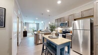 Located at 720 Verdae Boulevard in Greenville, SC, this one-bedroom, one-bathroom residence offers a thoughtfully designed single-floor layout with a comfortable and functional flow. The open-concept kitchen and living area serves as the heart of the home, where rich, dark-toned cabinetry contrasts beautifully with granite countertops and a suite of stainless steel appliances. A peninsula island with seating provides an ideal space for casual dining or entertaining. Light wood-style flooring runs throughout the main living areas, complementing the neutral, warm palette. Crown molding adds a refined architectural touch to the kitchen and living room. The living room is bright and welcoming, featuring large windows that invite natural light and a ceiling fan for year-round comfort. The spacious primary bedroom is carpeted for warmth and features a ceiling fan, large windows with outdoor views, and ample room to furnish generously. A dedicated closet offers practical storage. The full bathroom is well-appointed with dark wood vanity cabinetry, dual sinks, granite countertops, a large mirror with overhead lighting, and a glass-enclosed shower. Wood-look flooring and clean neutral walls complete the polished, contemporary feel of this Greenville residence.