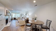 Located at 3200 Chestnut Ridge Drive in Pittsburgh, PA, this 2-bedroom, 2-bathroom single-floor residence offers a thoughtfully designed layout that maximizes functionality and comfort. The open-concept living and dining area features warm hardwood-style flooring, a textured ceiling, and natural light streaming through large windows dressed in sheer curtains, creating an inviting, airy atmosphere. A pass-through window with a granite-style ledge connects the living area to the kitchen, which is equipped with stainless steel appliances including a gas range, microwave, and refrigerator, complemented by white cabinetry. The spacious primary bedroom includes plush carpeting, a ceiling fan, and a natural light source, while the second bedroom offers versatility, shown here as a home office with built-in shelving and a ceiling fan. Both bathrooms are finished with clean, white tub-shower combinations with built-in shelving. Additional highlights include an in-unit laundry area and generous closet storage throughout — five closets in total. The overall ambiance is warm, neutral, and move-in ready, offering practical single-level living in a residential Pittsburgh community.