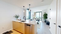 Located at 12 Church Street in New Rochelle, NY, this thoughtfully designed one-bedroom, one-bathroom residence offers a modern aesthetic with high-end finishes throughout. The open-concept kitchen and living area serves as the heart of the home, featuring warm-toned cabinetry, a sleek white waterfall island with an undermount sink, pendant lighting, and stainless steel appliances including a dishwasher. The living area is bathed in natural light through expansive floor-to-ceiling windows that frame sweeping panoramic views of the surrounding cityscape and waterway beyond. Light hardwood flooring runs continuously throughout, enhancing the bright, airy ambiance. The bedroom is a serene retreat, highlighted by a bold geometric accent wall, large windows with stunning views, and ample space for a full furniture arrangement. The bathroom is finished with full marble-style porcelain tile on both the walls and floors, complemented by a modern vanity with matte black hardware and a combined tub and shower. Additional features include a dedicated entrance with built-in storage, a hallway, two closets, and an in-unit laundry area, ensuring both comfort and practicality in this refined New Rochelle residence.