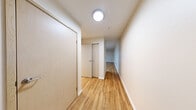 Located at 219 E Garfield St in Seattle's Capitol Hill neighborhood, this single-floor unit offers a thoughtfully utilized layout with warm hardwood flooring extending throughout every room. The open-concept living and kitchen area serves as the heart of the space, featuring stainless steel appliances including a full-size refrigerator and range, light wood cabinetry with ample storage, and a sliding glass door that leads to a private balcony with views of the surrounding neighborhood. The living area is bright and clean, with neutral white walls and a straightforward design that allows for flexible furniture arrangements. A dedicated hallway connects the main living space to the bathroom, which is equipped with a full soaking tub and shower combo, brushed nickel fixtures, a grab bar, and matching hardwood flooring that ties the space together. Recessed and flush-mount ceiling lighting provides consistent illumination throughout, and a wall-mounted thermostat ensures climate control. The overall ambiance is clean, modern, and functional, making this unit a practical and well-appointed option in the heart of Seattle.