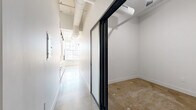 Located at 2801 Locust St, Unit 208 in St. Louis, MO, this two-bedroom, one-bathroom unit offers a distinctive industrial aesthetic with a thoughtful layout across a single floor. Polished concrete floors run throughout the space, lending a raw, urban character that pairs well with the clean white walls and bold black hardware accents.

The main living area is a standout feature, highlighted by large, multi-pane windows that flood the room with natural light and frame views of the surrounding St. Louis cityscape. Exposed structural elements and a sleek ceiling fan complement the loft-inspired design. The open feel of this area creates a versatile canvas for living and entertaining.

The two bedrooms offer private retreats, with the primary bedroom providing a cozy yet functional footprint. The hallway connecting the rooms features a sliding glass door with black metal framing, adding a contemporary touch, along with built-in shelving for added storage.

The bathroom rounds out the unit's practical offerings. Throughout the space, the combination of crisp white walls, concrete flooring, and minimalist design details creates a cohesive, modern industrial ambiance — ideal for those who appreciate clean lines and urban living in the heart of St. Louis.