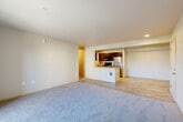 This two-bedroom, two-bathroom residence in Everett, Washington offers a thoughtfully designed single-level layout that maximizes functionality and comfort. The open-concept living room and kitchen area form the heart of the home, where plush carpeting in the living space transitions to durable wood-look flooring in the kitchen. The kitchen features dark-toned cabinetry, stainless steel appliances including a refrigerator, oven, and microwave, a peninsula with a built-in sink, and ample counter space — ideal for everyday cooking and entertaining. A hallway connects the living area to both bedrooms and bathrooms. The spacious primary bedroom benefits from generous natural light through a large window and direct access to its own bathroom, complete with a soaking tub, vanity with dark cabinetry, and tile flooring. The second bathroom mirrors a clean, functional design with a full tub-shower combination and tile floors. A dedicated walk-in closet with wire shelving provides abundant storage. Throughout the residence, neutral tones, recessed lighting, and clean finishes create a bright, modern ambiance well-suited for comfortable everyday living.