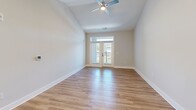 Located at 7100 Summerside Dr in Whitsett, NC, this single-floor, 2-bedroom, 2-bathroom residence offers a thoughtfully designed layout with contemporary finishes throughout. The open-concept kitchen and living area serves as the heart of the home, showcasing gray shaker-style cabinetry, granite countertops, a large central island with pendant lighting, a white subway tile backsplash, and a full suite of stainless steel appliances. Light hardwood flooring flows throughout the main living areas, enhancing the bright, airy atmosphere. The living room features vaulted ceilings, a ceiling fan, and glass French doors with a transom window above, opening onto a private balcony. The primary bedroom offers plush carpeting, a ceiling fan, and direct access to both a walk-in closet with wire shelving and a private en-suite bathroom. The en-suite is well-equipped with a granite-topped vanity with gray cabinetry, a large walk-in glass-enclosed shower, and hardwood-style flooring. The second bedroom is equally comfortable, with soft carpeting, natural light, and its own ceiling fan. Two closets provide generous storage throughout. Clean neutral tones, modern hardware, and quality finishes give this home a polished, move-in-ready appeal.