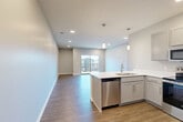 Located at 1920 Gregg Rd in Bellevue, Nebraska, this well-appointed one-bedroom, one-bathroom residence offers a thoughtfully designed open-concept floor plan. The combined living, dining, and kitchen area serves as the heart of the home, featuring warm wood-look plank flooring, recessed lighting, and a sliding glass door that opens to a private balcony with outdoor views. The modern kitchen is outfitted with gray shaker-style cabinetry, crisp white countertops, a peninsula with an undermount sink, and a full suite of stainless steel appliances including a refrigerator, range, microwave, and dishwasher. Stylish pendant lights above the peninsula add an elegant finishing touch. The spacious bedroom is carpeted for comfort and includes a ceiling fan, a large window for natural light, and access to a generously sized walk-in closet with dual hanging rods and built-in shelving. The bathroom features a wide vanity with white countertops, gray cabinetry with brushed nickel hardware, and a large mirror. Additional conveniences include a dedicated laundry area and multiple closets throughout, providing ample storage. The neutral color palette and clean modern finishes create a bright, welcoming ambiance throughout.