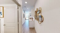 Located at 17501 Dallas Parkway in Dallas, TX, this thoughtfully designed one-bedroom, one-bathroom residence maximizes every inch of its compact footprint across a single floor. Light wood-style flooring runs throughout, tying the spaces together with a clean, contemporary aesthetic.

The open-concept kitchen and living area serves as the heart of the home. The kitchen features crisp white shaker cabinets with black hardware, a textured tile backsplash, stainless steel appliances including a refrigerator, electric range, and microwave, and a built-in dining nook with wall art — an efficient and stylish solution for everyday living. The living area benefits from multiple windows dressed with white blinds, allowing ample natural light, and is finished with a ceiling fan overhead.

The bedroom offers elevated ceiling height with high clerestory windows that draw in additional light, creating an airy feel despite the intimate scale of the room. A dedicated closet provides practical storage.

The bathroom is appointed with white shaker cabinetry, a single vanity with a clean white countertop, and a full tub-shower combo framed by vertical white subway tile. The entryway corridor, accented by a decorative gold-toned wall sculpture, sets a stylish tone from the moment you step inside.
