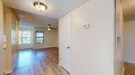 This single-floor residence offers a clean, updated interior with a cohesive design aesthetic carried throughout each room. Hardwood-style flooring in warm and light tones runs consistently across the living areas and bedrooms, providing a polished and easy-to-maintain foundation. The layout flows naturally from an entry hallway — equipped with a wall-mounted thermostat and a ceiling light fixture — into the main living space, which features a ceiling fan and windows that invite natural light and outdoor views.

The kitchen stands out as a functional highlight, outfitted with white shaker-style cabinetry, granite-look countertops, stainless steel appliances including a refrigerator, dishwasher, and range, recessed lighting, and a window above the sink for added brightness.

The bedrooms are generously sized, each featuring large windows that fill the rooms with natural light. Textured ceilings, white panel doors, and neutral wall tones give the rooms a clean, versatile feel. One bedroom includes a walk-in closet with arched double doors, while another features track lighting as an additional design touch.

The bathroom is neatly finished with a tiled tub-shower combination, a granite-top vanity with white cabinetry, and chrome fixtures, maintaining the updated aesthetic found throughout the rest of the space.