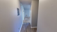 Located at 421 Opelika Rd in Auburn, Alabama, this single-floor unit offers a practical and efficiently organized layout across three bedrooms and four bathrooms. The interior features a mix of wood-style vinyl plank flooring in the hallways and wet areas, transitioning to carpet in the bedrooms and living spaces, all beneath textured ceilings throughout.

The kitchen is designed with a pass-through counter that opens to the carpeted living area, providing an open sightline between the two spaces. It includes a range, sink, and ample upper cabinetry with warm wood-toned finishes. Two hallways connect the rooms and provide access to the electrical panel and HVAC system.

The primary bedroom is a well-proportioned space that receives natural light through a window with blinds, and features carpet flooring. The remaining two bedrooms are similarly finished with carpet and neutral-toned walls, offering flexible use. All four bathrooms include tub/shower combinations with clean white surrounds and vinyl or tile flooring.

A standout feature of the unit is the private balcony, which overlooks a lush, tree-lined outdoor area, offering a peaceful natural view. The unit also includes a dedicated closet for added storage. This space is well-suited for shared living arrangements in the Auburn area.