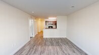 Located at 13135 Masons Bridge Rd in Woodbridge, VA, this one-bedroom, one-bathroom residence offers a thoughtfully designed layout that maximizes every square foot. The open-concept living and kitchen area serves as the heart of the home, featuring durable wood-look flooring throughout, neutral-toned walls, and clean-lined architecture that creates a bright, cohesive atmosphere. The kitchen is equipped with dark espresso cabinetry, granite countertops, a peninsula breakfast bar, and black appliances including a range and refrigerator. The spacious bedroom features a large window that brings in natural light and offers views of the surrounding community, complemented by a dedicated walk-in closet with built-in shelving and hanging rods for ample storage. The bathroom continues the modern aesthetic with granite countertops, a dark vanity, and wood-look flooring. A standout convenience is the in-unit laundry area, which houses a stacked GE washer and dryer alongside a water heater, all neatly tucked within a dedicated closet space. Clean white walls, consistent flooring, and functional design choices throughout lend the residence a fresh, move-in-ready appeal.