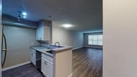Located at 1700 Palmer St in Durham, NC, this single-floor unit offers a well-designed, functional layout with a cohesive modern aesthetic throughout. The open-concept kitchen flows seamlessly into the living area, creating a connected and versatile space. The kitchen is outfitted with white cabinetry, granite countertops, a subway tile backsplash, stainless steel appliances including a refrigerator and electric range, and a peninsula with an overhang that doubles as a breakfast bar. Track lighting overhead enhances both task and ambient illumination. The spacious living area features rich hardwood-style flooring and a window that allows natural light to fill the room. Neutral gray walls throughout the main living spaces provide a clean, modern backdrop. The bedroom is carpeted for added comfort, with a window offering natural light and access to a closet. The bathroom includes a granite-topped vanity with white cabinetry, a combination tub and shower, and hardwood-style flooring that ties in with the rest of the unit. Textured ceilings are present throughout, and clean white trim and baseboards add a polished finish to every room. The unit's straightforward, single-level layout ensures easy accessibility and efficient use of space.