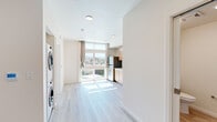 Located at 2701 Shattuck Ave in Berkeley, CA, this thoughtfully designed single-floor unit offers a clean, modern aesthetic throughout. Light-toned wood-style flooring runs seamlessly across all areas, complementing the crisp white walls and recessed lighting that give the space an airy, well-lit feel.

The open main area connects the living space to a functional kitchenette, which features warm-toned light wood cabinetry, a stainless steel refrigerator, a built-in sink with clean countertops, and large floor-to-ceiling windows that flood the space with natural light and frame sweeping views of the Berkeley Hills and surrounding neighborhood rooftops.

A dedicated alcove houses a full-size stacked washer and dryer unit, providing convenient in-unit laundry. A wall-mounted mini-split system ensures year-round climate comfort. The bathroom is finished in a neutral palette with light wood-look tile flooring, a pedestal sink, and a full toilet — clean and functional in its design.

The bedroom area benefits from oversized windows that deliver an abundance of natural light and picturesque hillside views, creating a serene and uplifting atmosphere. The overall design of this unit prioritizes brightness, efficiency, and a connection to the natural surroundings of the Berkeley landscape.