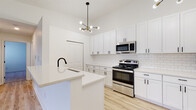 Located at 2644 Creekwood Cir in Moraine, Ohio, this single-floor residence presents a clean, contemporary aesthetic throughout. The kitchen serves as a standout feature, showcasing white shaker cabinetry with matte black hardware, light quartz countertops, and a classic white subway tile backsplash. Stainless steel appliances — including a range, over-the-range microwave, and refrigerator — complement the space, while a peninsula with an undermount sink and a modern sputnik-style chandelier add functional style. Light wood-look flooring flows throughout the kitchen, creating a bright, cohesive look.

The bedrooms are carpeted in a neutral tone, offering a comfortable feel, and include windows that bring in natural light. One bedroom features a built-in closet alongside a stacked washer and dryer unit, providing convenient in-unit laundry. The bathroom is tastefully updated with wood-look tile flooring, a dark navy vanity, white tiled tub-shower surround, and matte black fixtures. The overall design palette — crisp whites, neutral tones, and black accents — gives the home a fresh, modern character throughout.